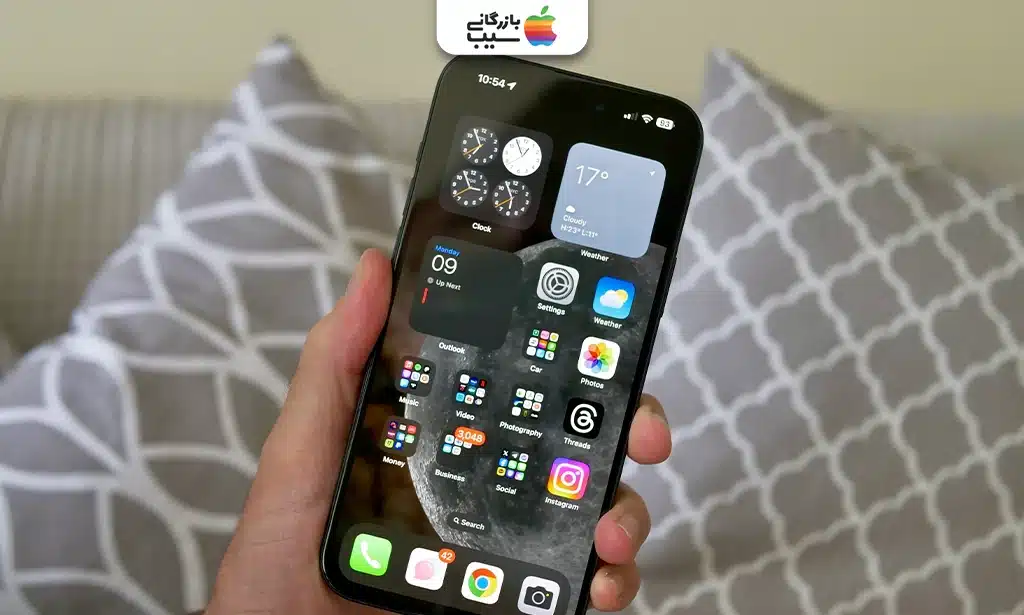 تصویر صفحه اصلی iOS 17 روی آیفون 15 پلاس با آیکون‌های مرتب و تمیز