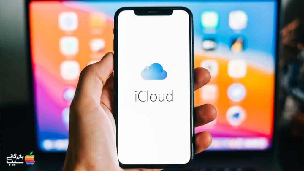 آقایی در حال اتصال آیفون به کامپیوتر با Apple iCloud است.