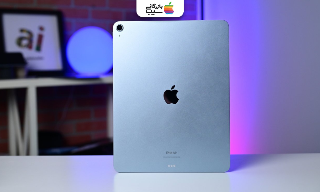 نمای پشت iPad Air آبی با دوربین تکی، لوگوی اپل و بدنه آلومینیومی در محیطی با نورپردازی رنگی