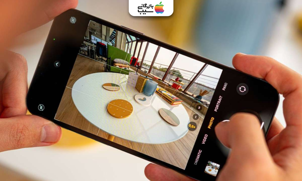 نمای نزدیک دست‌های کاربر هنگام عکاسی از میز و فضای داخلی با دوربین آیفون